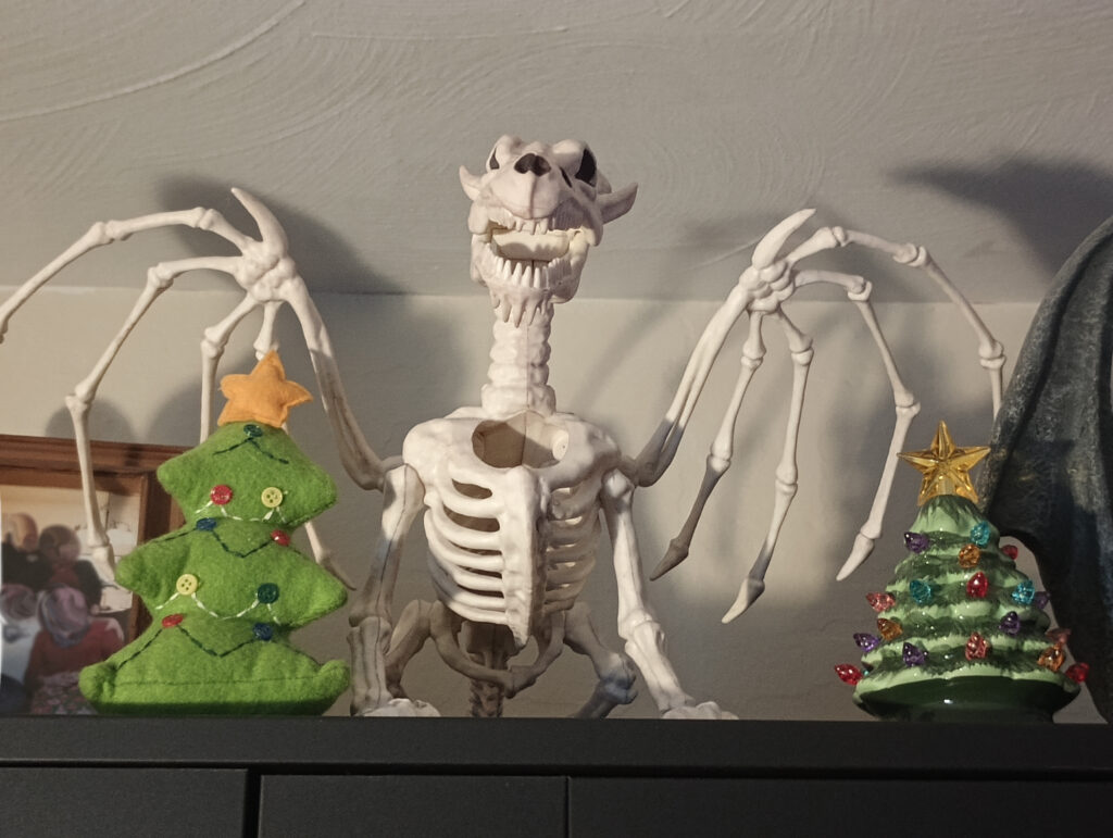 A skeletal dragon model standing next to some Christmas Trees