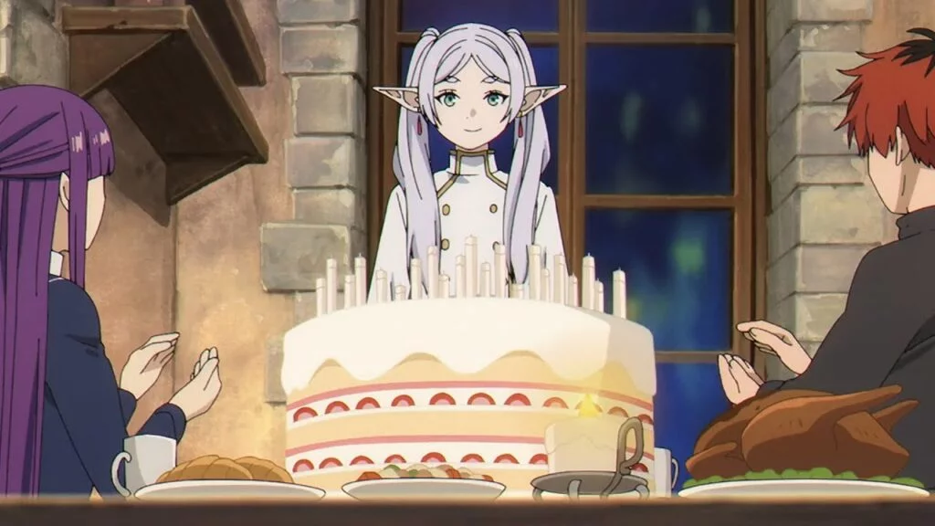 Frieren, Fern, and Stark from "Frieren: Beyond Journey's End" sharing a large strawberry and cream birthday cake topped with several candles