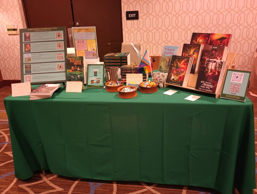 A table covered with a green tablecloth and several signs and copies of books by J. Robert Matthewson and S.E. Robertson/C.A. Moss.